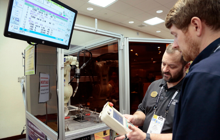  Two OTC DAIHEN employees working with robotic welding equipment 